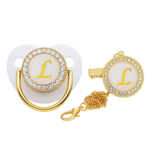 Close-up of golden luxury baby pacifier with crystal rhinestones and letter L detail