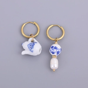 Detail of asymmetric earrings with blue and white porcelain teapot and pearl charm