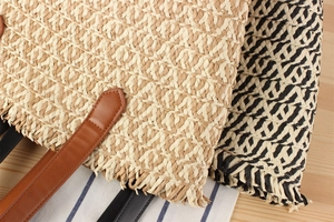 Close-up of woven straw bags with fringe detail and brown leather straps for women