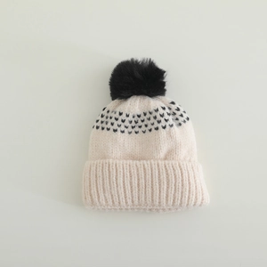 Détail du bonnet en maille chaude montrant le pompon et la texture jacquard épaisse