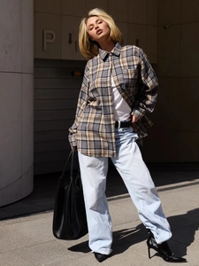 Street style shot of a grey and yellow plaid shirt paired with light blue jeans and boots