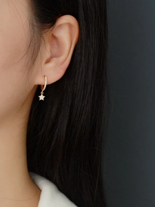 Close-up of gold star earrings with sparkling cubic zirconia on a female model