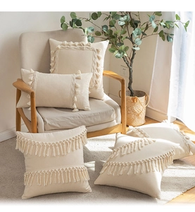 Detailed close-up of cream woven cushions with decorative tassels and fringe accents