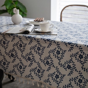 Detailed close-up of blue floral cotton linen tablecloth with decorative tassel edges
