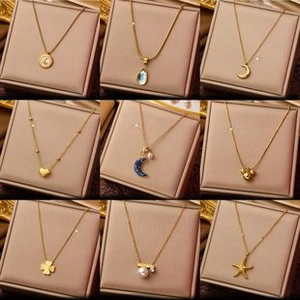 Detailed grid of golden pendant necklaces with moon, star, and clover designs in pink boxes