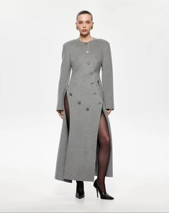 Détail d'un manteau gris ajusté en laine avec fentes latérales hautes et ourlet asymétrique