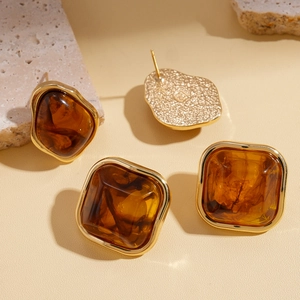 Boucles d'oreilles carrées en résine marron sur un support décoratif en pierre