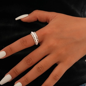 Detail of gold plated hollow ring with pearls on model finger against black background