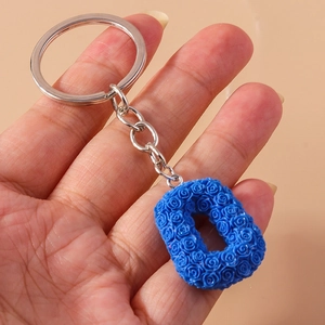 Detailed close-up of blue rose pattern letter O keychain held to show scale and texture