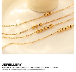 Close-up of gold beaded anklet in 18K gold plated titanium steel on a ceramic plate