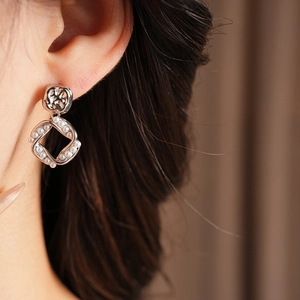 Close-up of model wearing silver-plated square stud earring with delicate pearl drop