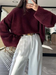 Women's burgundy knit long sleeve sweater in a loose fit paired with white trousers