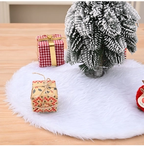 Close-up of white plush Christmas tree skirt on a wooden table with festive holiday decor