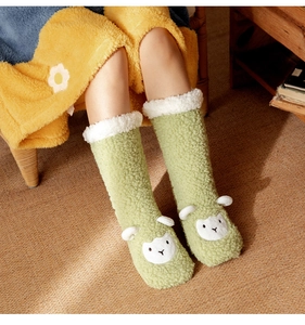 Close-up of green plush floor socks with white faux fur trim and cute sheep design