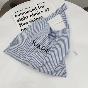 Flat lay of blue and white striped canvas tote bag with Sunday Summer Night lettering