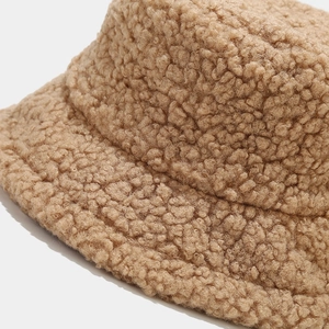Macro shot of thick lamb wool texture and neat stitching on a warm camel bucket hat