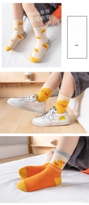 Detailed view of child crew socks featuring cute yellow duck patterns in beige and orange