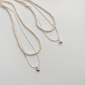 Close-up of double-layer freshwater pearl necklace with silver heart and bead pendants