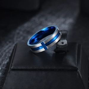 Macro detail of men's blue and silver cross ring with brushed metal finish