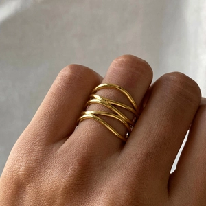 Close-up of golden multilayer wavy stainless steel ring worn on finger with glossy finish