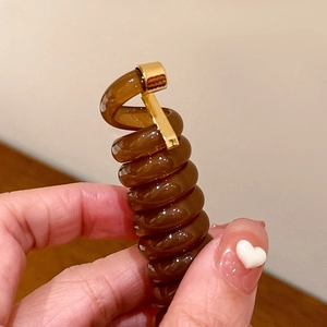 Gros plan de l'élastique spirale ambre avec boucle métallique dorée élégante