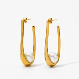 Detailed close-up of U-shaped golden earrings featuring a lustrous white pearl accent