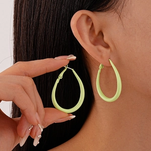 Close-up of light green oval geometric hoop earrings worn to show matte finish and size