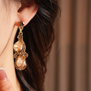 Détail macro de boucles d'oreilles vintage dorées avec cristaux de champagne