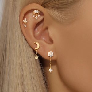 Close-up of gold moon and star earring set with zircon inlay on model's ear