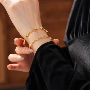 Dettaglio del bracciale a sfere placcato oro 18k con fiori in zircone sul polso