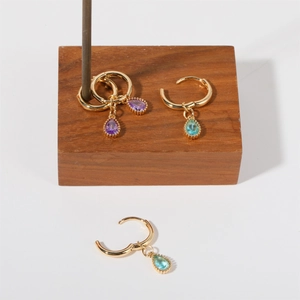 Detail of teardrop gemstone drop earrings in purple and blue with gold beaded edges