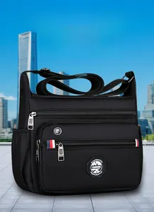 Detail view of black nylon shoulder bag with multi-zipper pockets and adjustable strap