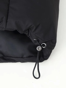 Macro view of adjustable elastic drawstring and silver metal toggle on black parka hem