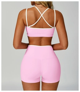 Dettaglio del set yoga rosa con reggiseno sportivo incrociato e pantaloncini a vita alta