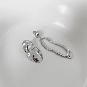 Macro shot of 925 sterling silver asymmetric earrings with liquid metal texture finish