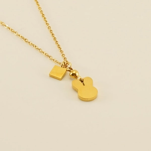 Detail of gold rabbit pendant and square tag necklace with polished metal finish