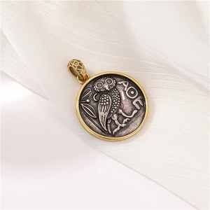 Close-up of vintage Greek owl pendant in antique silver and gold finish on soft fabric