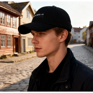 Outdoor street view of a black cotton baseball cap with white JIAN MAO YE printed text