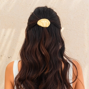 Detailed back view of a gold oval liquid metal hair clip worn on a half-up hairstyle