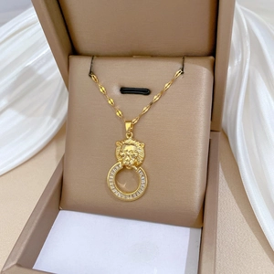 Detailed shot of a gold lion head pendant with a zircon-set ring in a premium jewelry box