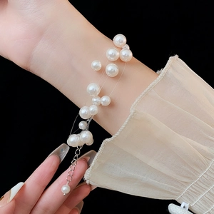 Detail of multi-layer staggered pearl bracelet with glossy finish on a female wrist