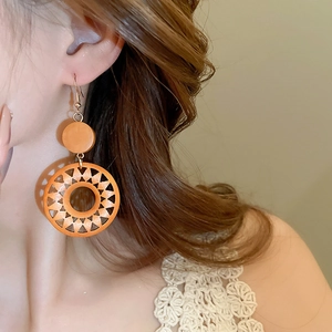 Detailed view of bohemian vintage wooden sun-carved round clip-on earrings in orange