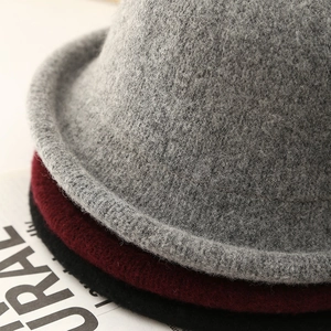 Close-up of stacked wool felt bucket hats in grey, burgundy and black with rolled edges