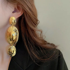 Close-up of gold layered oval earrings with hammered metal texture on model