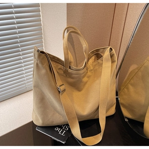 Detail of khaki canvas tote bag with reinforced handles and natural light shadow texture