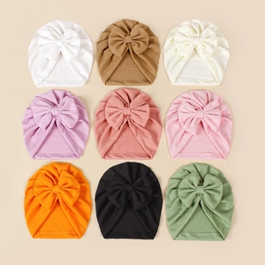 Macro shot of assorted baby knit hats featuring large bows in nine vibrant color options