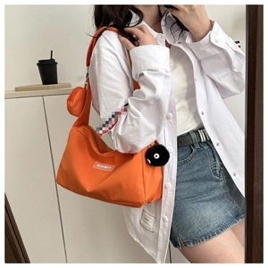 Détail du sac bandoulière en nylon orange avec mini porte-monnaie et charm boule en peluche