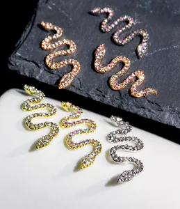 Macro shot of 3D snake nail art charms with sparkling zircons on a dark rock background