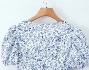 Detail of floral puff sleeve dress featuring a hidden back zipper on a wooden hanger
