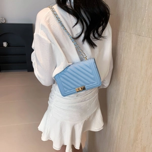 Rear view of a model wearing a light blue quilted crossbody bag with gold-tone hardware